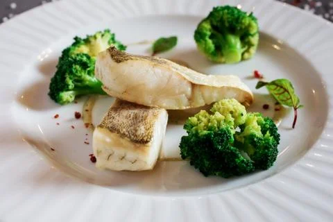 Close up view of the delicious dinner made of white fish and broccoli on the Stock Photos