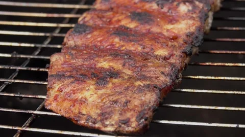 Close-up view of the delicious ribs flipped on the grill grid with kitchen tongs Stock Footage 169606267