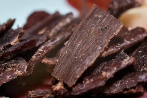 A close-up view of delicious savory beef jerky pieces piled together on a pla Stock Photos