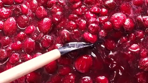 A close-up view of delicious strawberry jam being stirred in a pot, showcasing Stock Footage 330376396