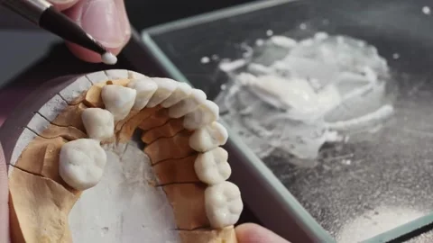 Close up view of dental technician draws white ceramics glaze on prosthesis of Stock Footage 136026355