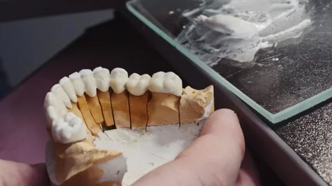Close up view of dental technician draws white ceramics glaze on prosthesis of Video stock 136026375
