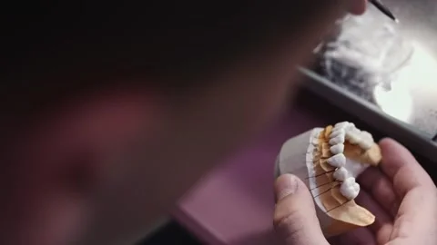 Close up view of dental technician draws white ceramics glaze on prosthesis of Stock Footage 136026388