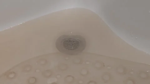 Close up view of dirty, brown water flowing and swirling down a clogged drain Stock Footage 341491357