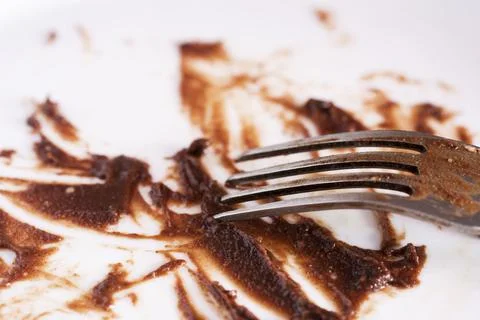 Close up view of dirty fork and white plate eaten chocolate sauce stain. Fini Stock Photos