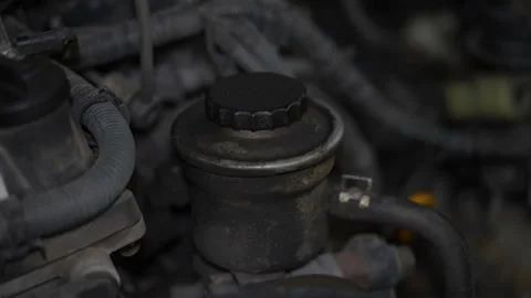 A close-up view of a dirty power steering fluid reservoir Stock Footage 343552475