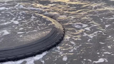 A close up view of a discarded car tire on a beach in Dagupan city. Video stock 260946668