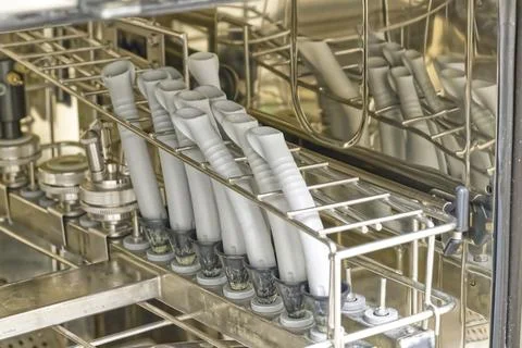 A close-up view of a dishwasher rack filled with gray plastic tubes, likely.. Stock Photos