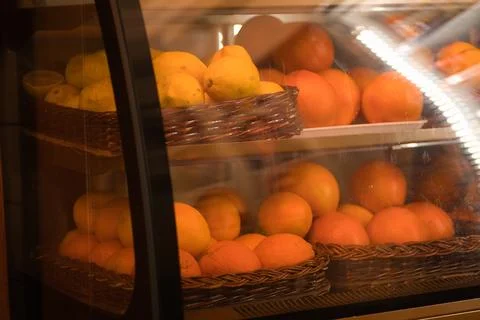 Close-up view of a display case filled with baskets of fresh lemons and oranges Stock Photos