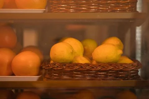 Close-up view of a display case filled with baskets of fresh lemons and oranges Stock-Fotos