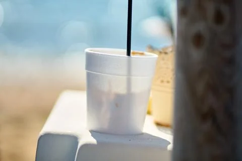 Close-up view of a disposable white plastic cup with iced coffee sitting on.. Stock Photos