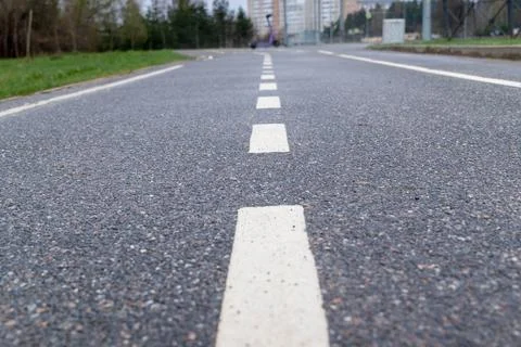 Close-up view of dividing lines along an empty asphalt bike path in a city pa Stock Photos