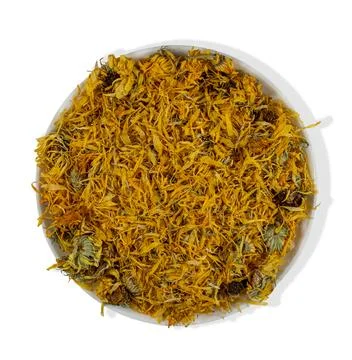 Close view of dried calendula petals and flowers in a white bowl for herbal.. Foto stock