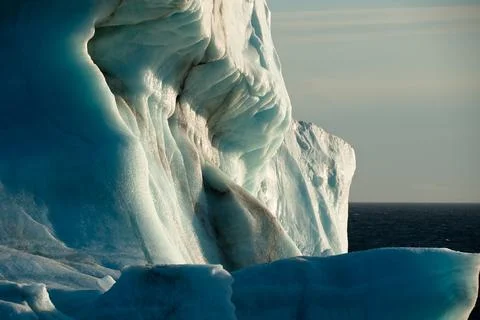 Close view of a drifting Arctic Iceberg taken from a ship shows sun shining  Stock Photos