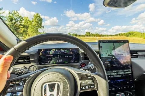 Close-up view of driver operating Honda e:Ny1 electric SUV with scenic highway Stock Photos