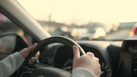 Close-up view of a driver's hands on the steering wheel, navigating through h Stockbeeldmateriaal 275280218