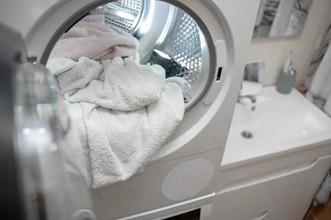 Close up view drying machine with washed and dried towels in and door open. Stock Photos