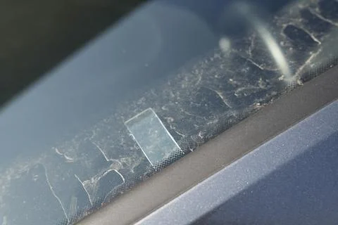 Close-up view of a dusty car windshield featuring a small sticker and dirt Stock Photos