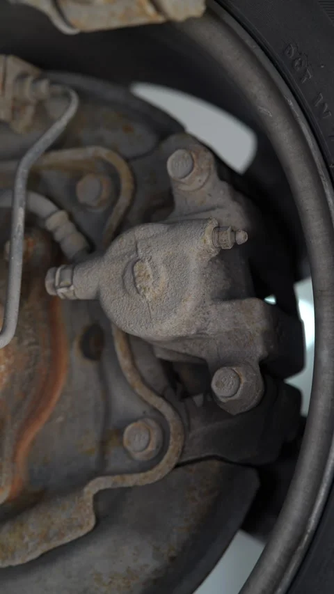 A close-up view of a dusty, single-piston car brake caliper 動画素材 343552218
