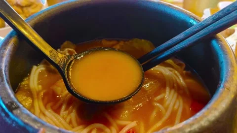 Close up view eating hot steamy boiling tomato rice noodle soup with lettuce and 動画素材 318258342