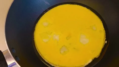 Close-up view of egg mixture sizzling in a hot frying pan on high heat, cooking  Video stock 318129918