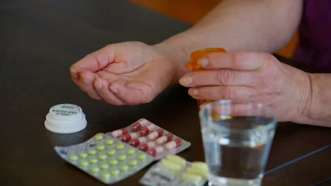 Close up view of elderly hands pouring pills from an orange prescription bottle Stock Footage 331034266
