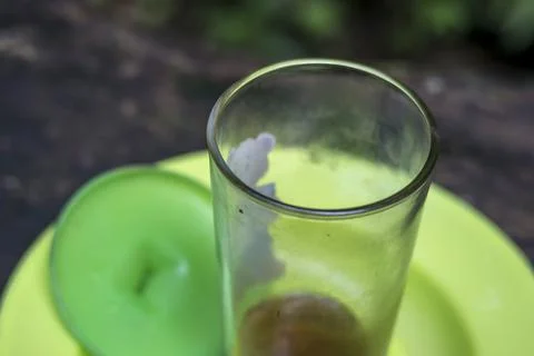 Close up view of empty glass on a green plate. Glass of leftover tea on a tra Stock Photos