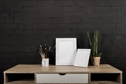 Close up view of empty photo frames, plant in flowerpot and drawing equipment Stock Photos