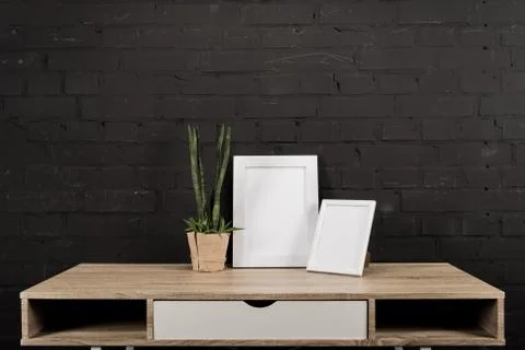 Close up view of empty photo frames and plant in flowerpot on wooden table Stockfoto's