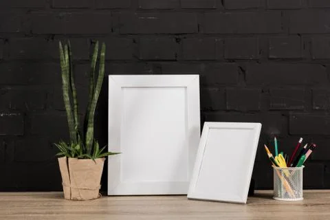 Close up view of empty photo frames, pencils and plant in flowerpot on tablet Stockfoto's