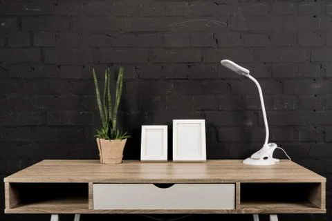 Close up view of empty photo frames, plant in flowerpot and table lamp on woo 写真素材