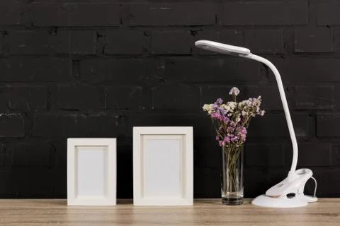 Close up view of empty photo frames, flowers in vase and table lamp on wooden 写真素材
