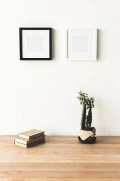 Close up view of empty photo frames hanging on wall at workplace with books a Stockfoto's