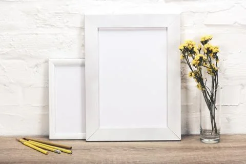 Close up view of empty photo frames, pencils and flowers in vase on wooden su 写真素材