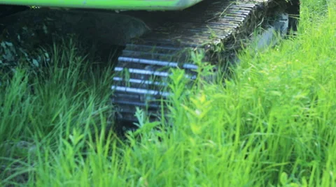 Close up view of excavator track wheels spinning and moving on grassy ground. Video stock 66073878