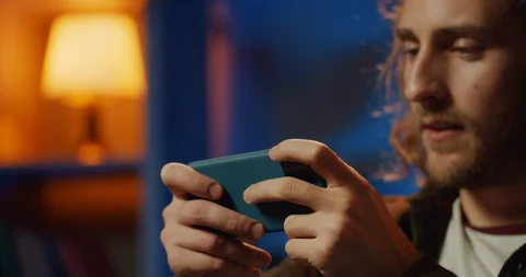 Close up view of excited young man playing game on his smartphone.Cheerful 库存影片 129806176