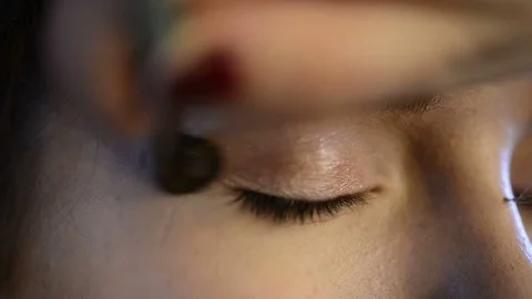 Close up view on eye of beautiful model getting makeup with eyeshadow Stock Footage 74153216