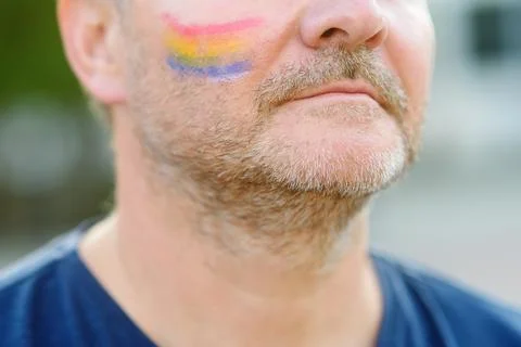 Close up view of face man activist with painting rainbow on cheek during LGBT Stock Photos