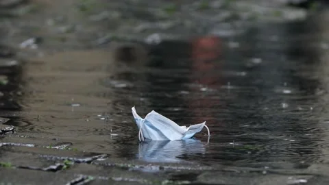 Close-up view of face mask in puddle during rain Stock Footage 139876577