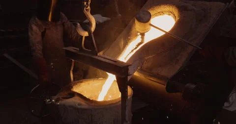 Close-up view of a factory worker pouring molten metal out a smelting furnace Stock Footage 140734449
