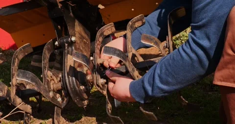 Close-up view of a farmers hands securing the rotary tiller blades on a two 스톡 동영상 333759756