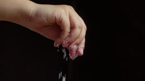 Close-up view of a female chef's hand sprinkles salt on food on a black bac.. Stock Footage 329703144