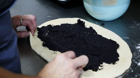 Close up view of a female cooker rolling up a pastry with poppy seeds. Sweets Stock Footage 99360244