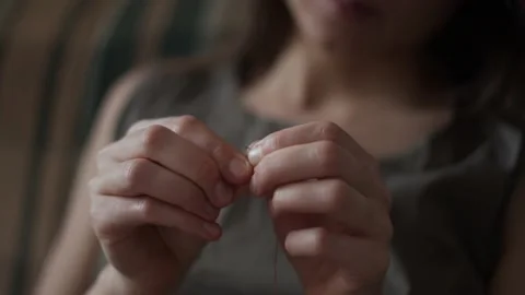 Close-up view of female hands inserting a thread into a needle hole for sewing Stock-Footage 151970991