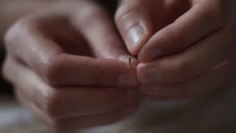 Close-up view of female hands inserting a thread into a needle hole for sewing Stock Footage 151972383
