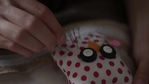 Close-up view of female hands inserting pins into pin cushion in shape of owl Stock Footage 151974526
