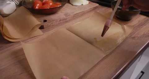 Close-up view of female hands preparing parchment paper for baking, using a Stock Footage 329866575
