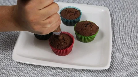 Close-up view of female hands puts the cream pastry bag on chocolate cupcakes Stock Footage 89117957
