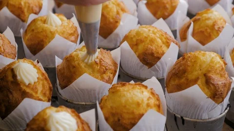 Close-up view of female hands puts the cream from pastry bag on cupcakes. Stock Footage 108100559