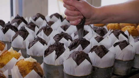 Close-up view of female hands puts the cream on chocolate cupcakes Stock Footage 108100853